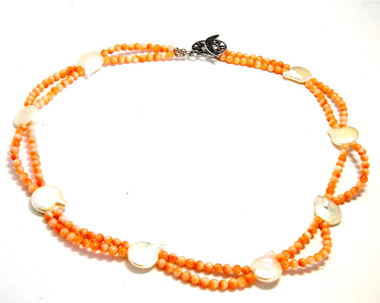 Vintage coral beads in shades of orange complimented by fresh water coin pearls in a 17 inch necklace.