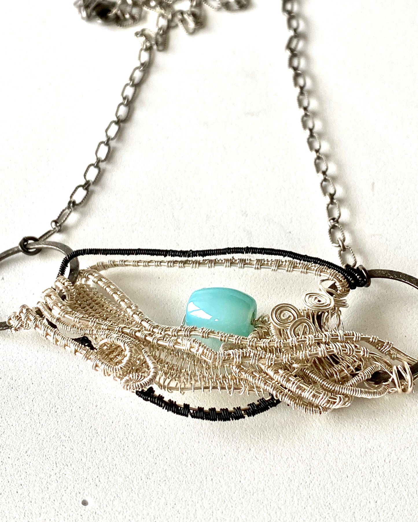 Fine silver and black pendant with a peruvian opal light blue stone for accent. Hanging from an oxidized sterling silver chain.