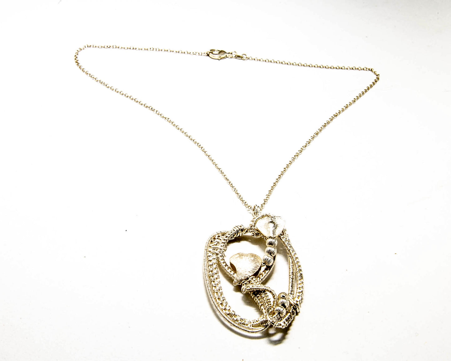 Fine silver woven pendant with two brushed silver hearts incorporated within the frame.